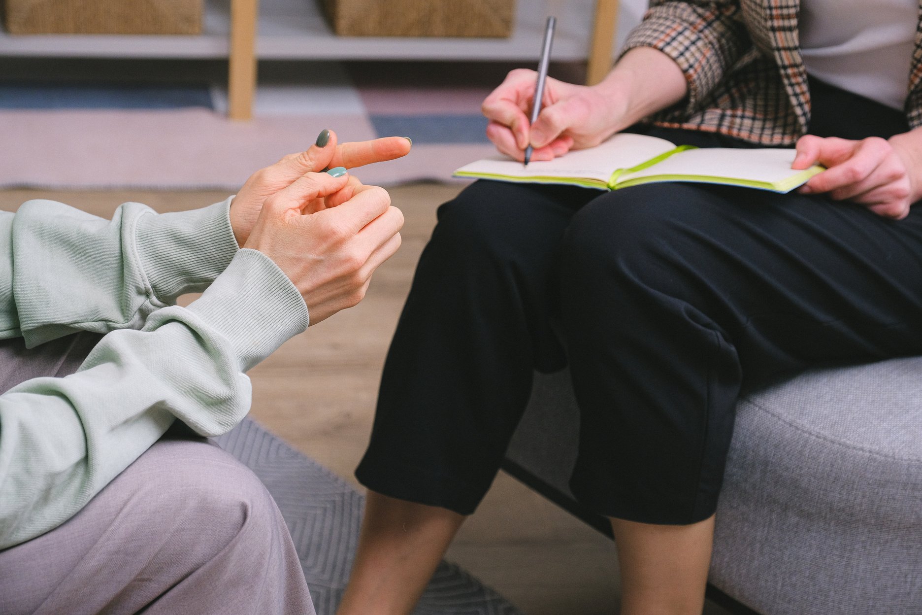 Anonymous female therapist and client sitting in armchairs during session in modern office